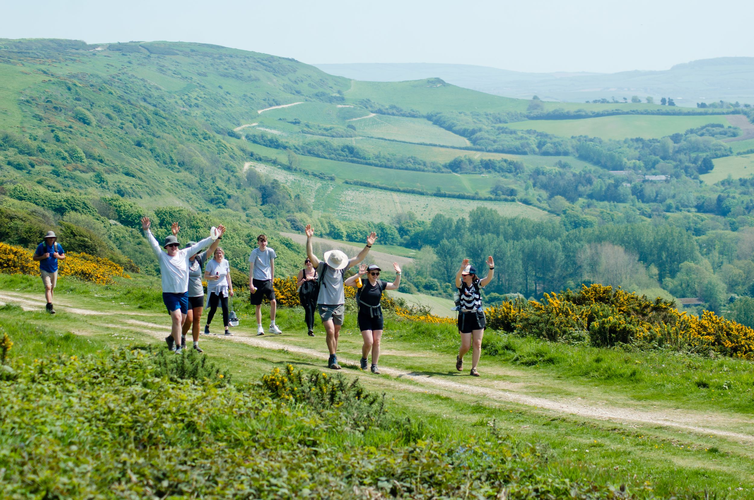 Participants celebrating while hiking on scenic hilltop trail with valley views.