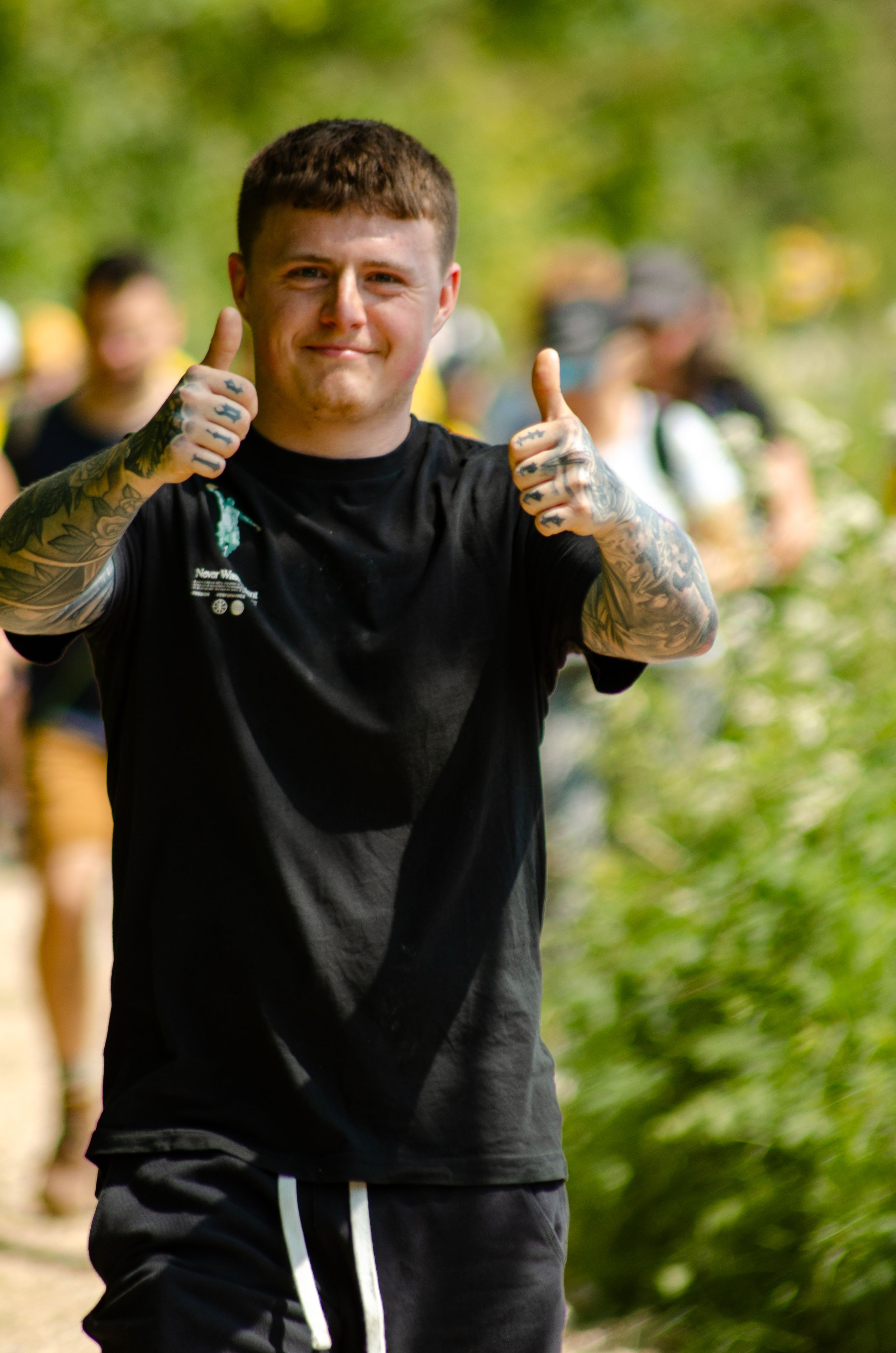 Participant giving thumbs up gesture during outdoor hiking event.