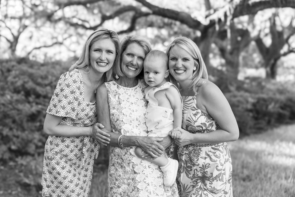 Black and white portrait of four women in floral dresses outdoors.