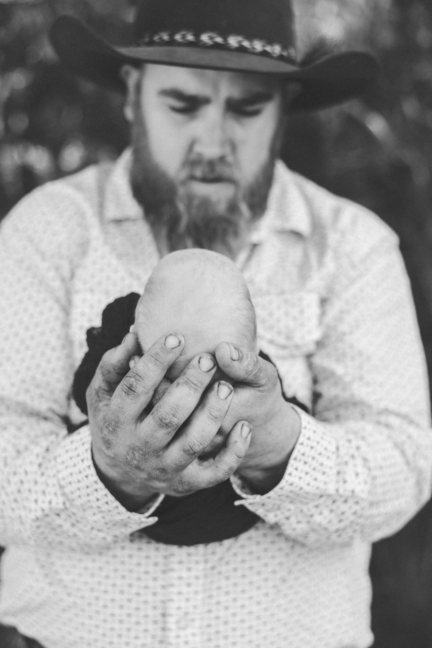 Black and white portrait of person holding newborn baby with gentle care.