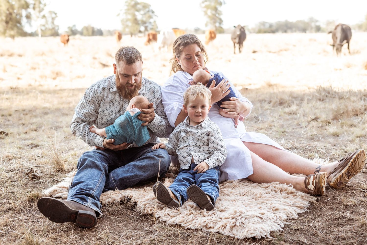 Family relaxing together outdoors in casual clothing during golden hour photoshoot.