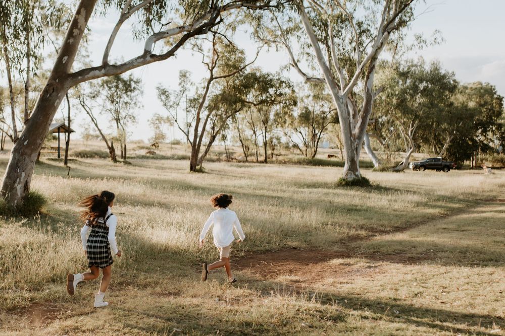 boy and girl run through the fields as the sunsets in Mount Isa