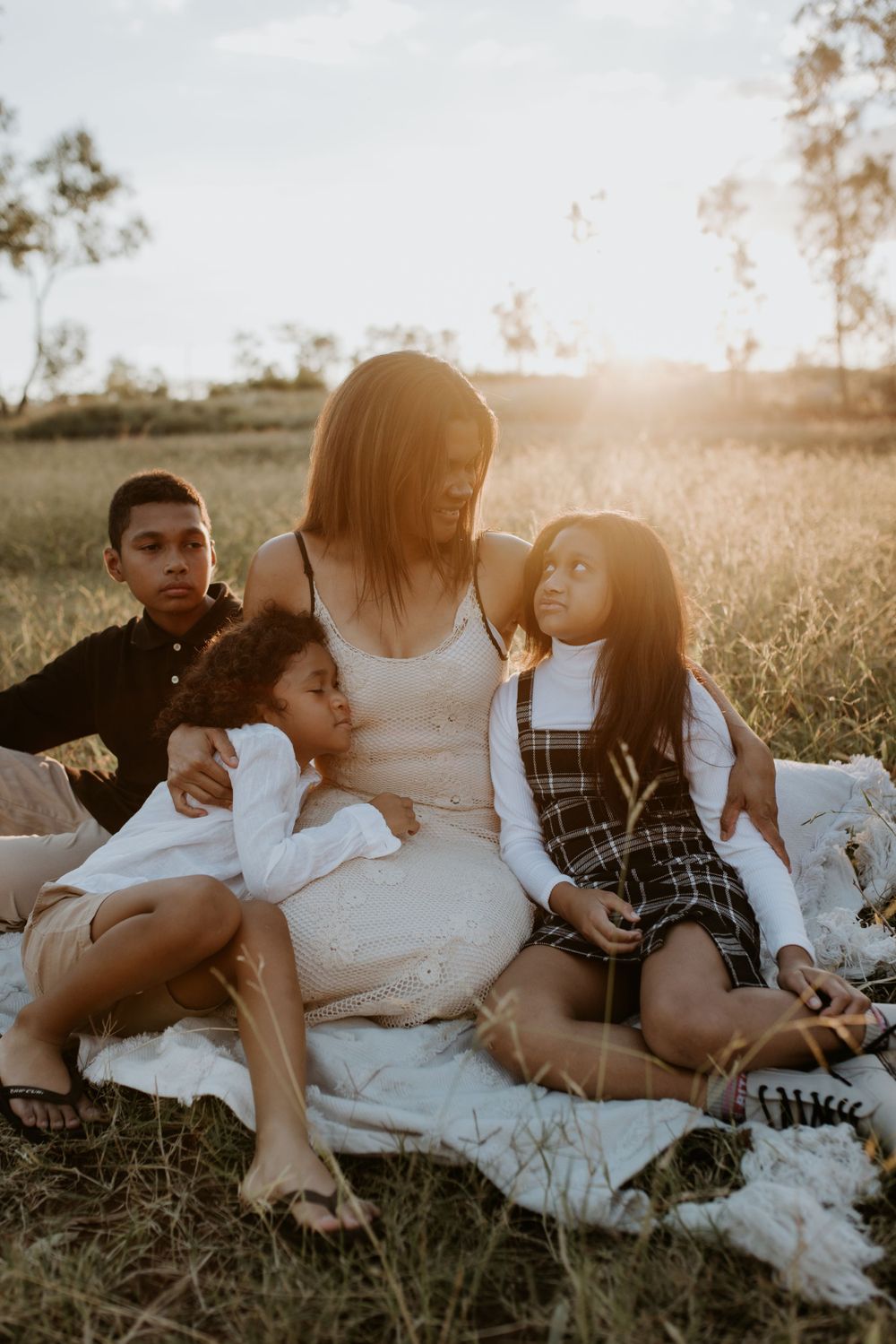 mother and kids sit as the sunsets behind them in Mount Isa