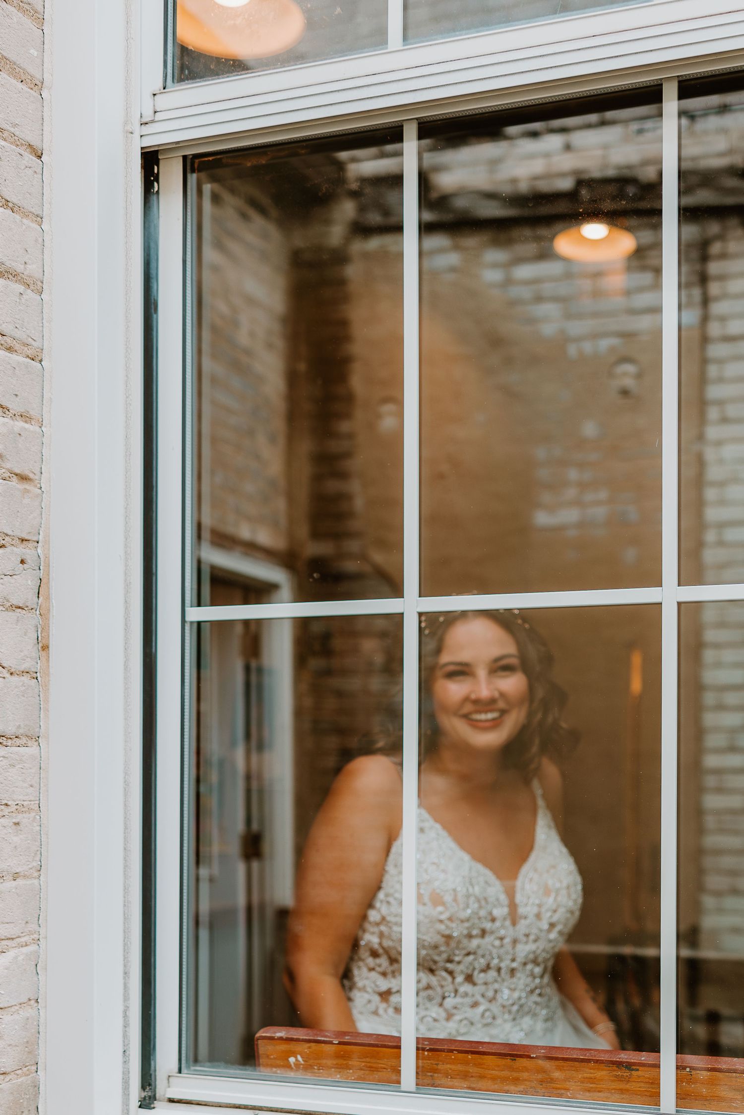View through window panes of someone in a white lace dress.