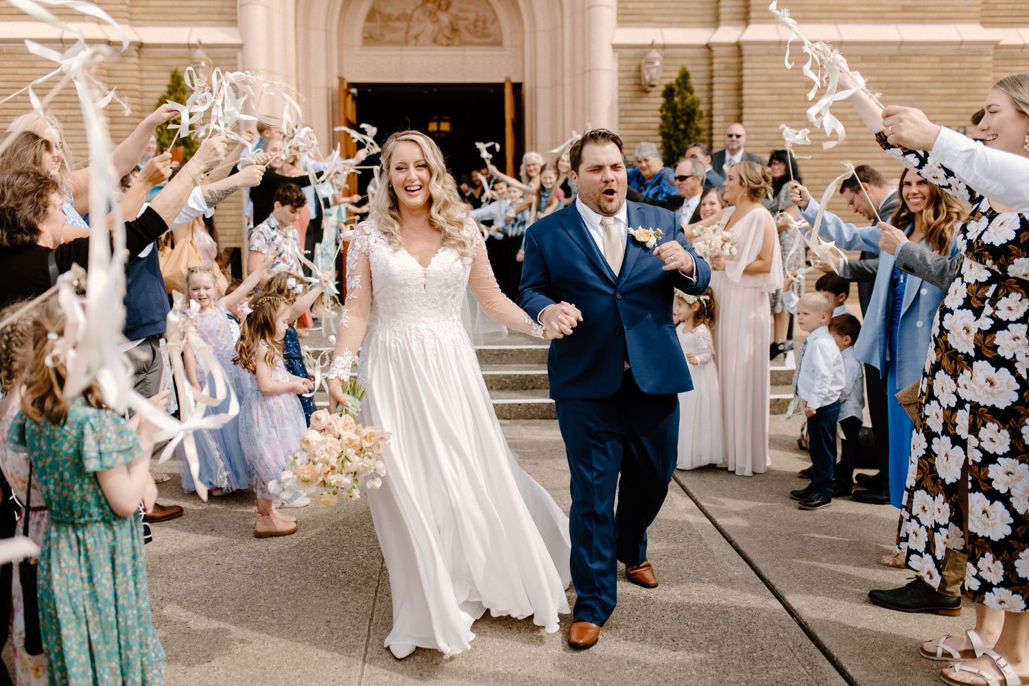 A newlywed couple exits their wedding ceremony while guests throw confetti.