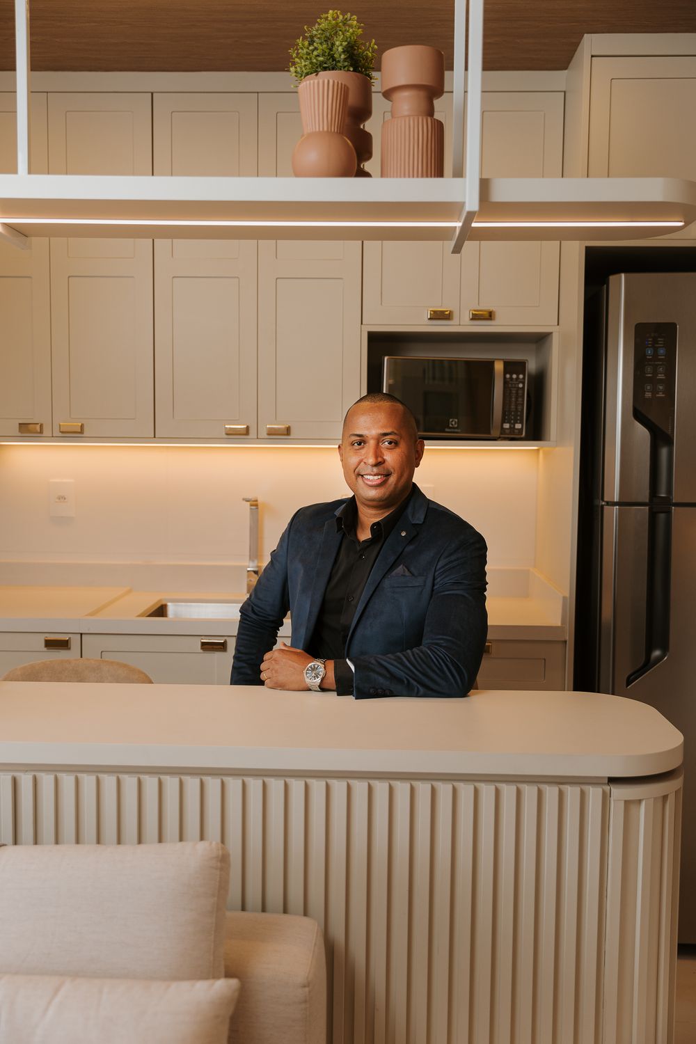 Executive poses in modern kitchen with white cabinetry and contemporary design.