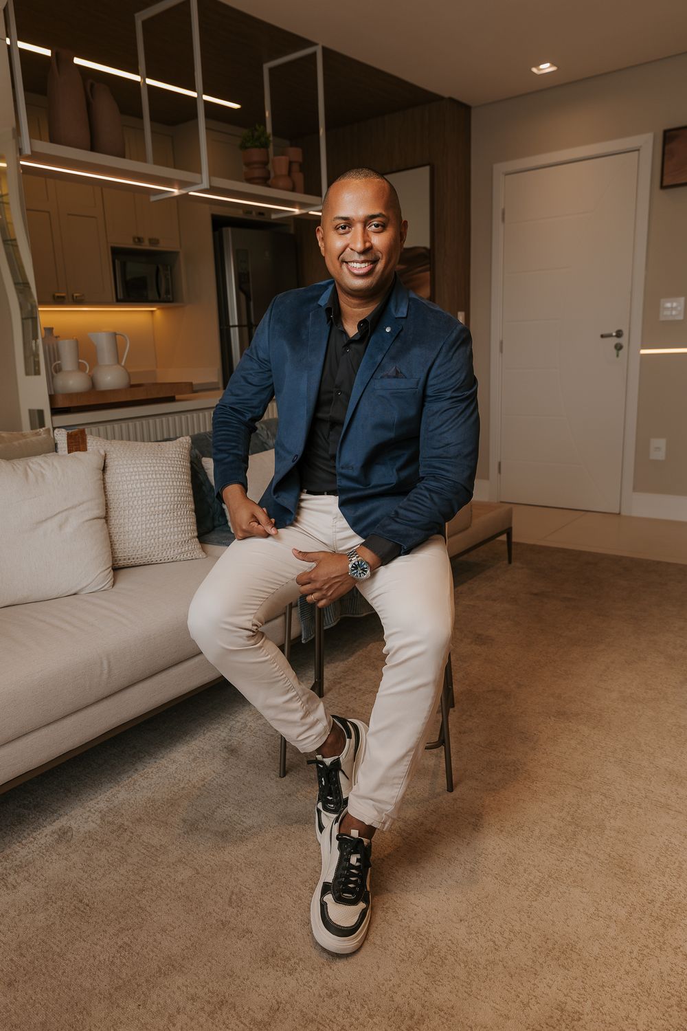 Business casual portrait session in modern living room with sneakers and blazer.
