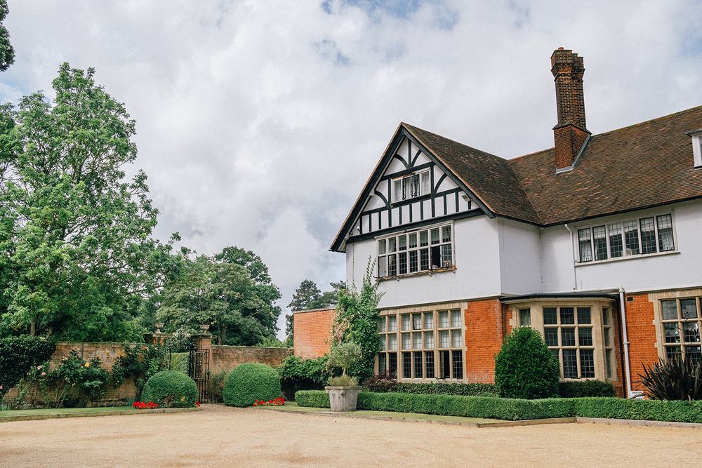 Elegant Tudor-style wedding venue with manicured gardens and white exterior.