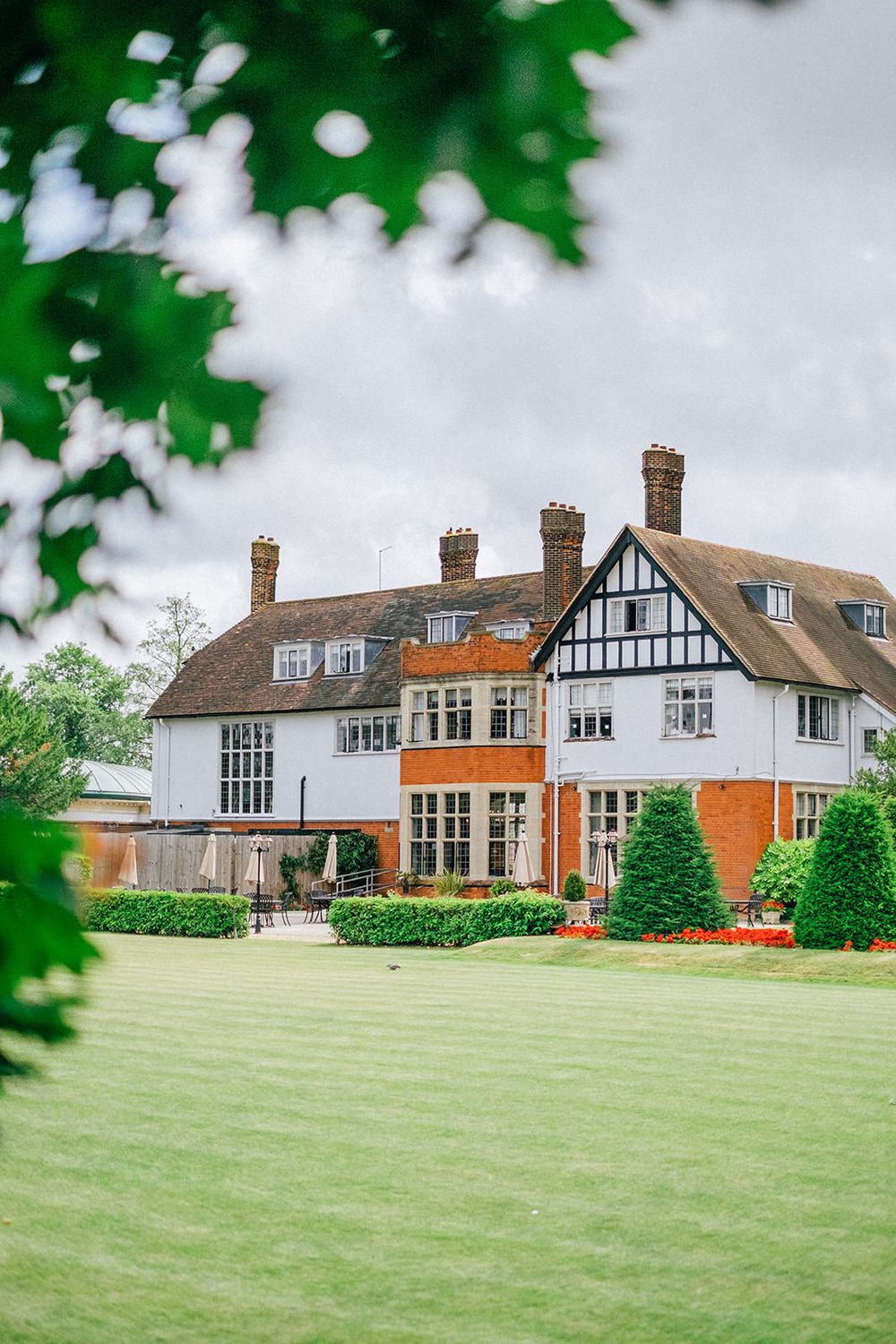 Tudor-style mansion with white and orange exterior set on manicured lawns.