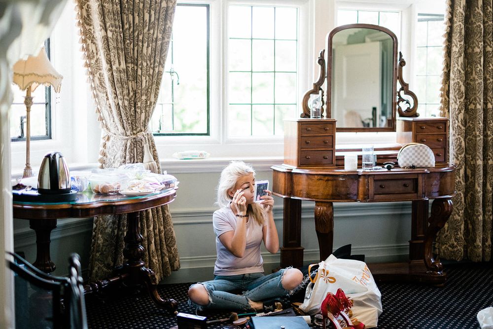Wedding morning preparations in a vintage-styled dressing room with antique vanity and floral curtains.