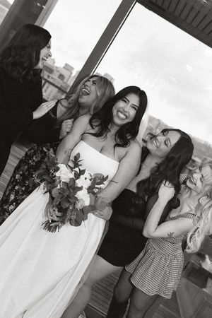 A group of celebrants share joyful laughter while posing together at a special event.