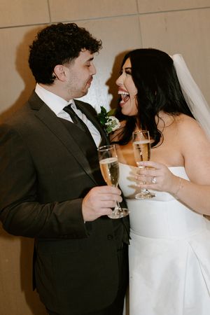 A couple shares a joyful moment with champagne flutes at their wedding celebration.