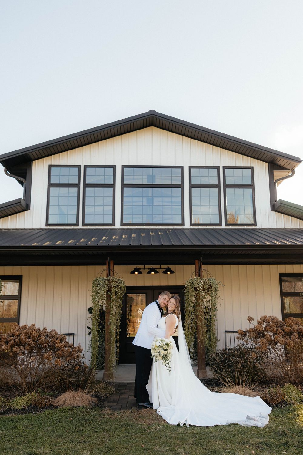 A modern white and black wedding venue exterior with large windows is shown in a panoramic sequence of shots.