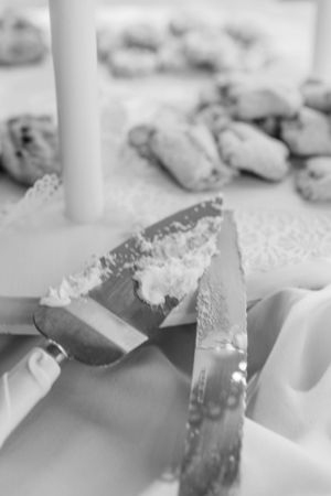 Close-up of spreading butter or cream cheese with a knife in black and white.