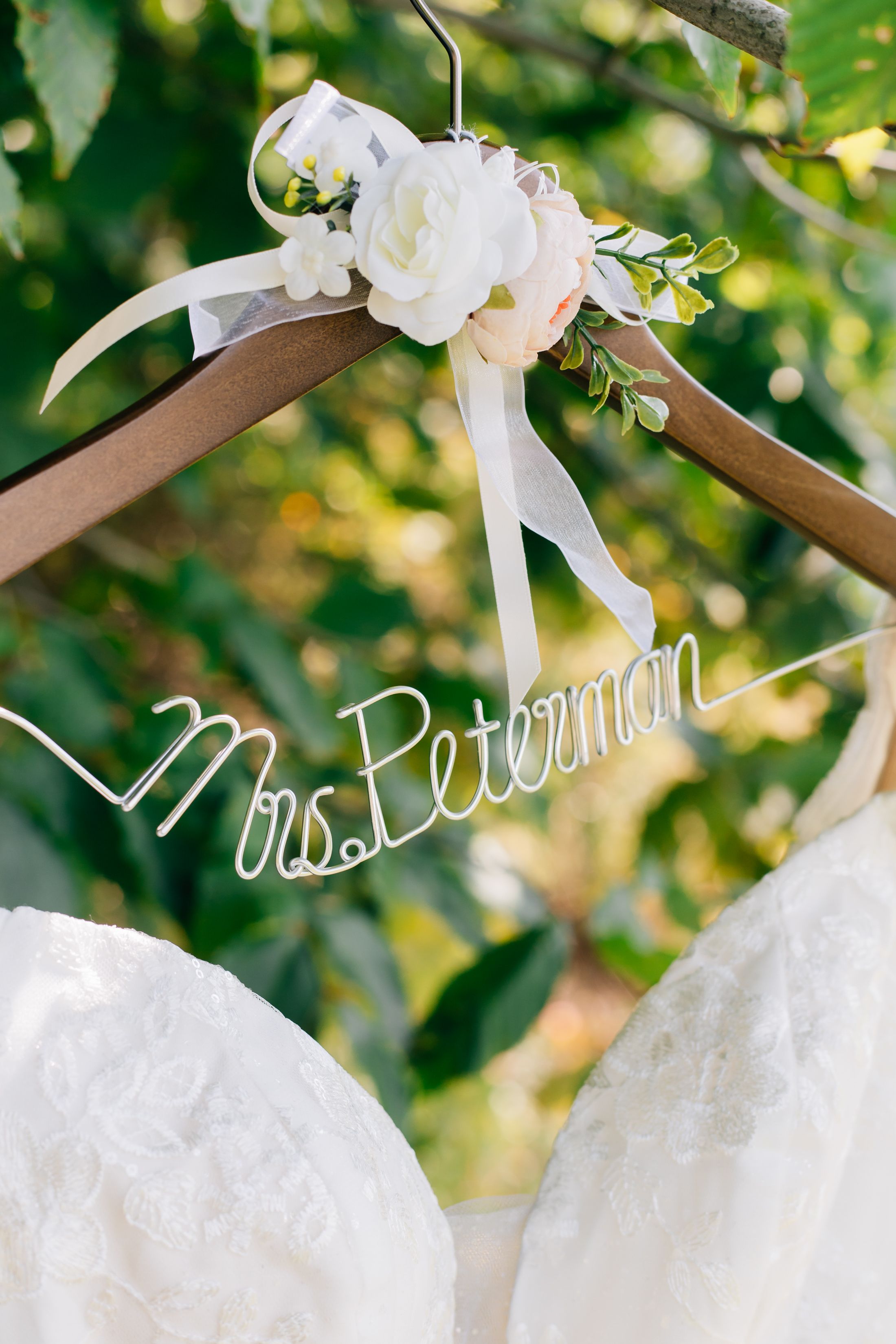 White wedding dress hangers with personalized names displayed in a row.