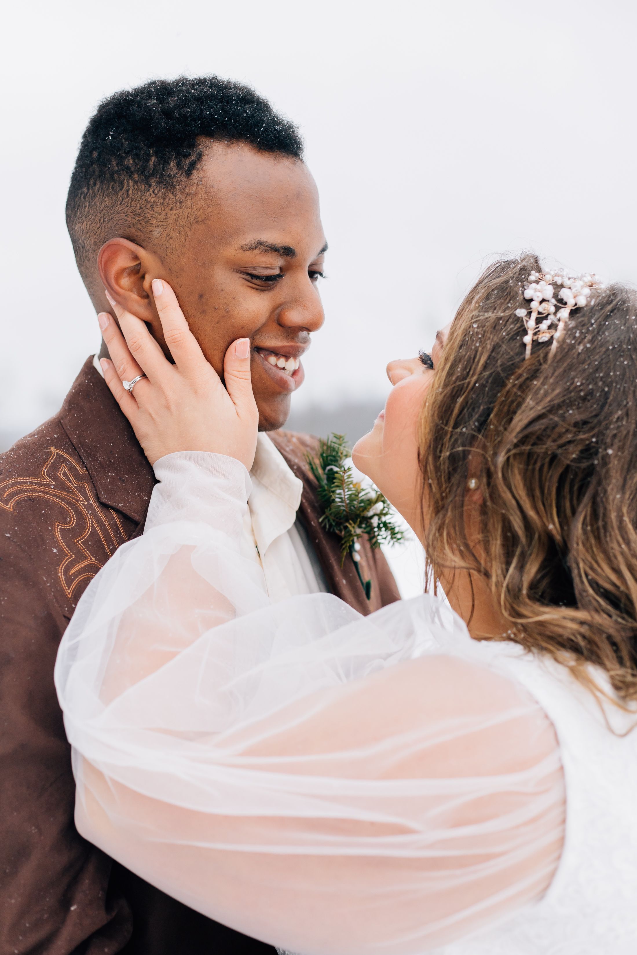 A winter wedding couple shares tender moments while wrapped in flowing white veil.