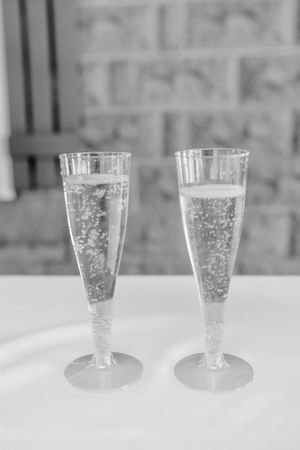 Two elegant champagne glasses filled with sparkling wine on a white tablecloth.