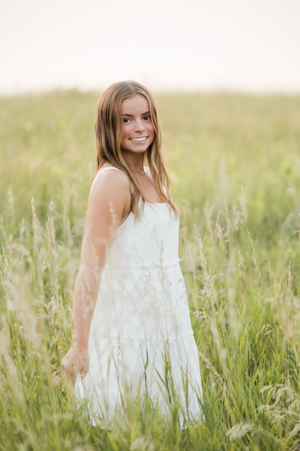 White lace dress photographed in tall summer grass during golden hour.