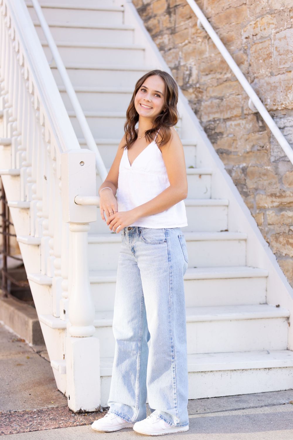 A bright outdoor portrait against white stairs and brick wall architecture.