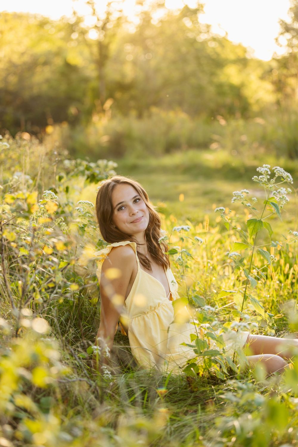 A dreamy summer portrait in a wildflower meadow with golden light filtering through tall grasses.