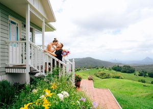 White farmhouse with mountain views and colorful garden flowers.
