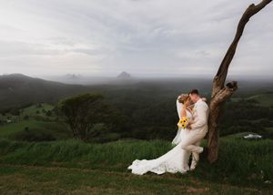A panoramic view of rolling green hills and misty mountains stretches across the horizon at dusk.