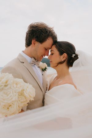 Romantic wedding portrait series showing couple in soft light with white roses.