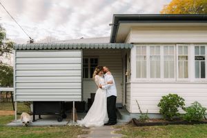 A couple shares a tender moment together in front of a white house on their wedding day.