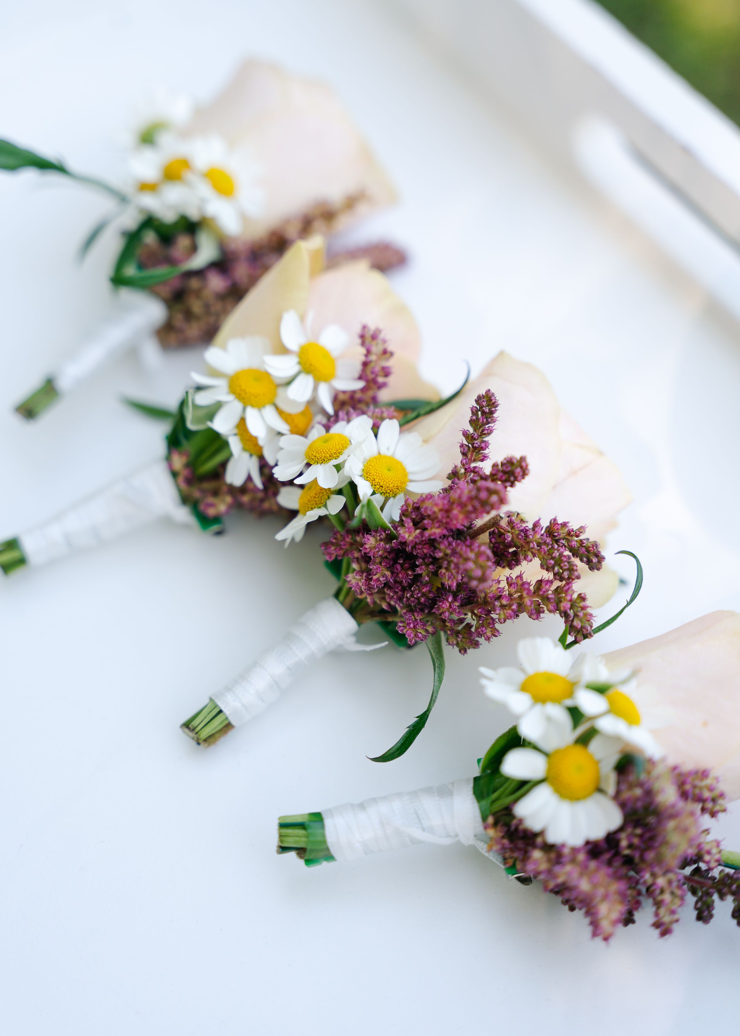 Delicate white daisy flowers and purple astilbe arranged in a minimalist floral composition against a white background.