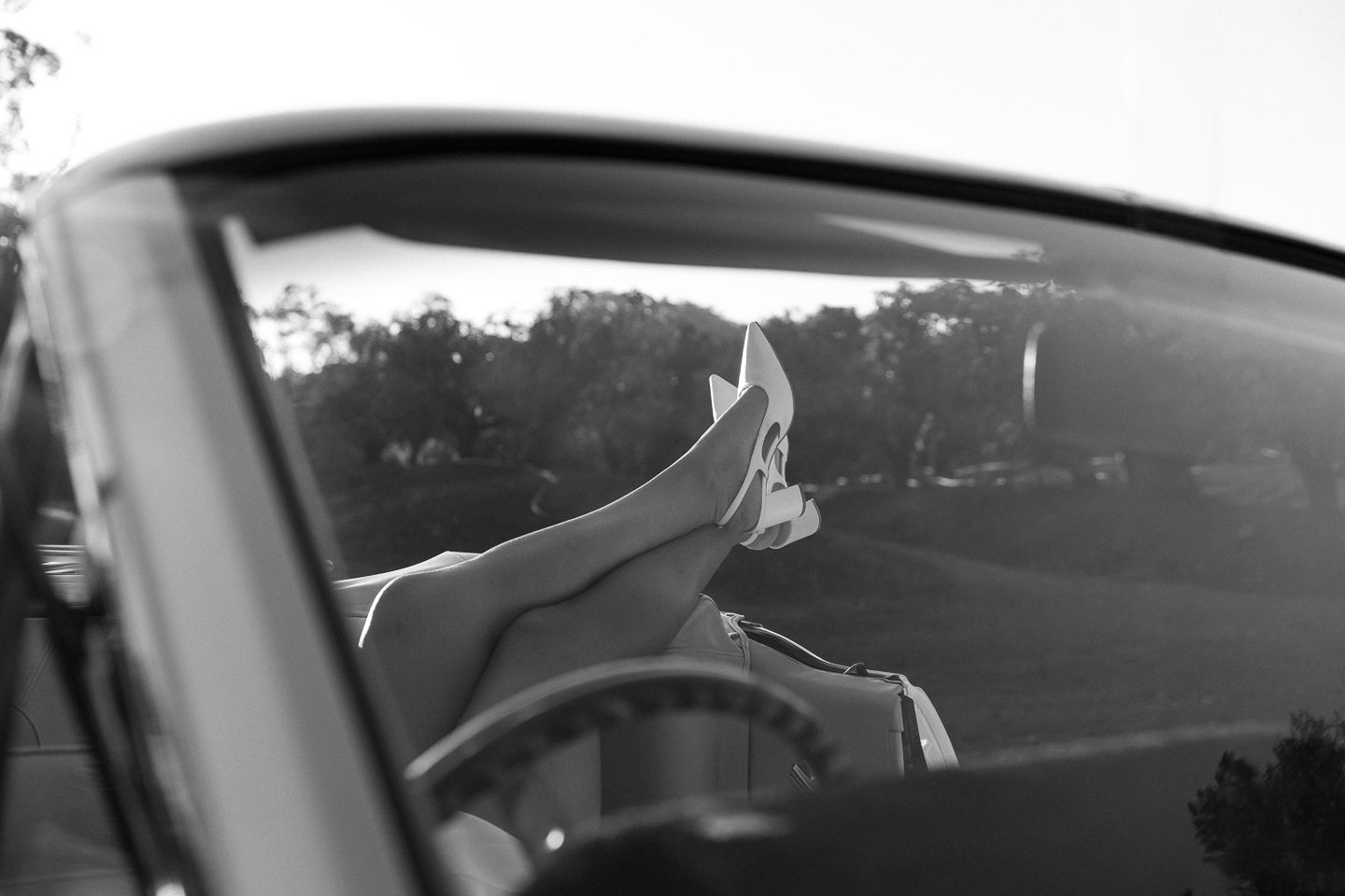 A black and white panoramic view of cars parked at a drive-in movie theater at dusk.