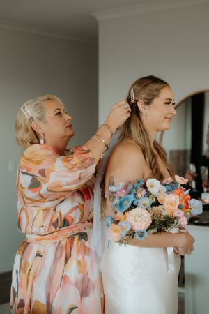 Wedding preparation moment with bride holding floral bouquet in peach and blue tones.