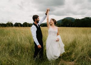 Couple dancing together in a golden wheat field at sunset.