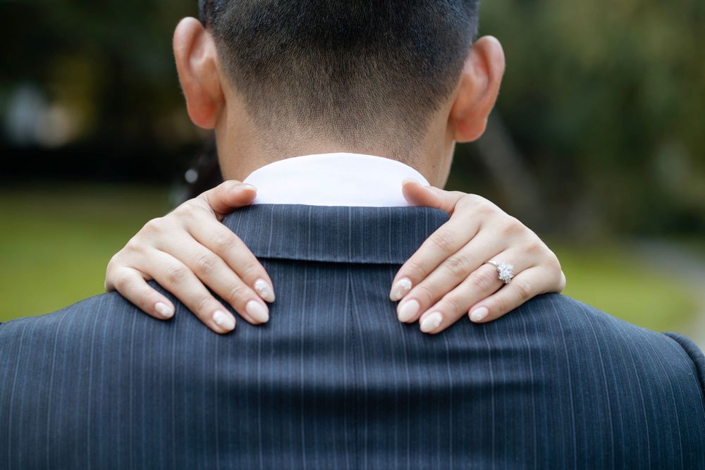 A series of images showing hands resting on shoulders in formal attire from behind.