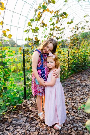 Sweet embrace captured in greenhouse surrounded by climbing plants and vines.
