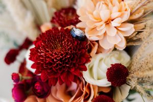 Close-up of wedding bouquet with deep red chrysanthemums and peach-colored flowers.