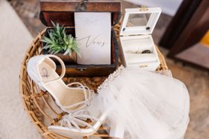 Wedding accessories including veil and shoes arranged in wooden basket.