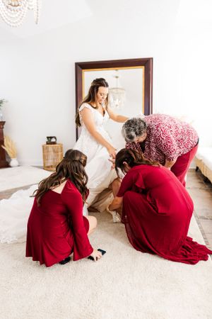 Wedding party helps adjust bride's dress during preparation.