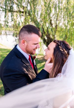 Romantic wedding moment captured under weeping willow trees.