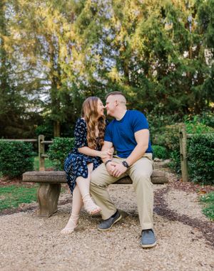 Romantic couple sitting close together on wooden bench in garden setting.