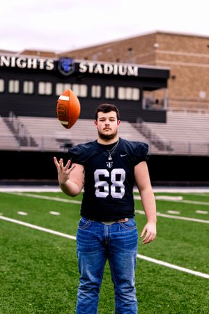 Football player in jersey number 68 tossing football at Knights Stadium field.