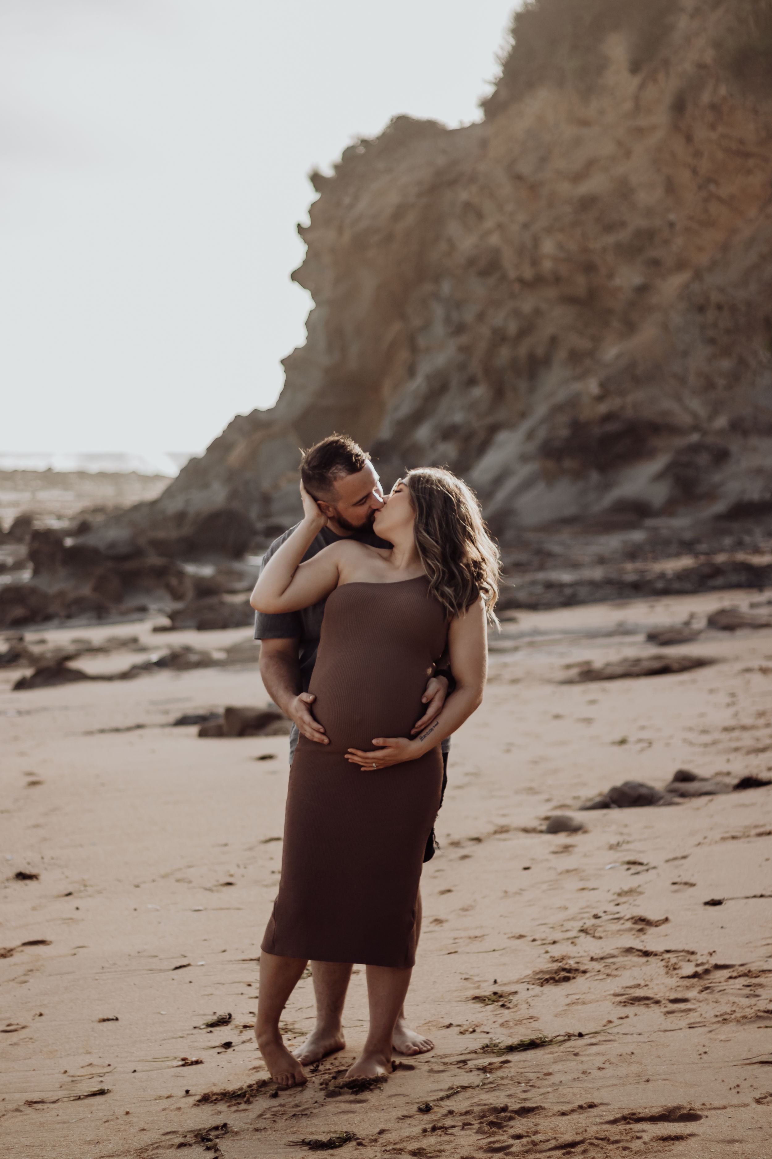 Pregnant woman looking back at partner holding her belly.