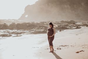 Pregnant woman holding her belly on the beach.