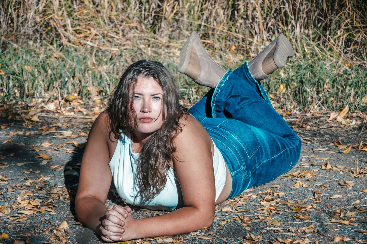 A relaxed outdoor portrait amid fallen autumn leaves and dried grass.