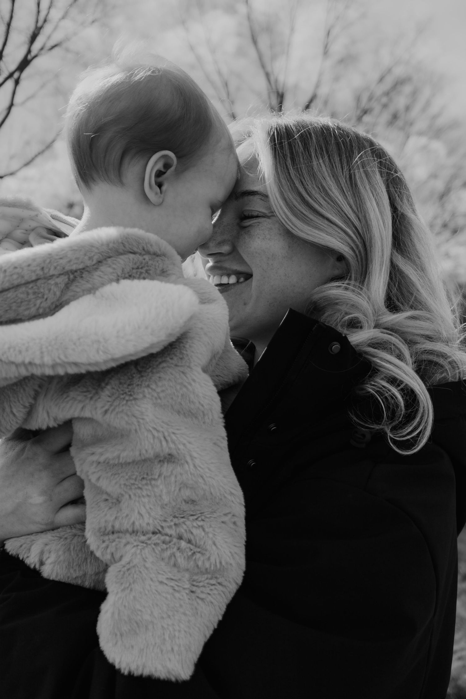 A tender black and white photo showing an intimate moment of affection and connection between a mum and her baby.