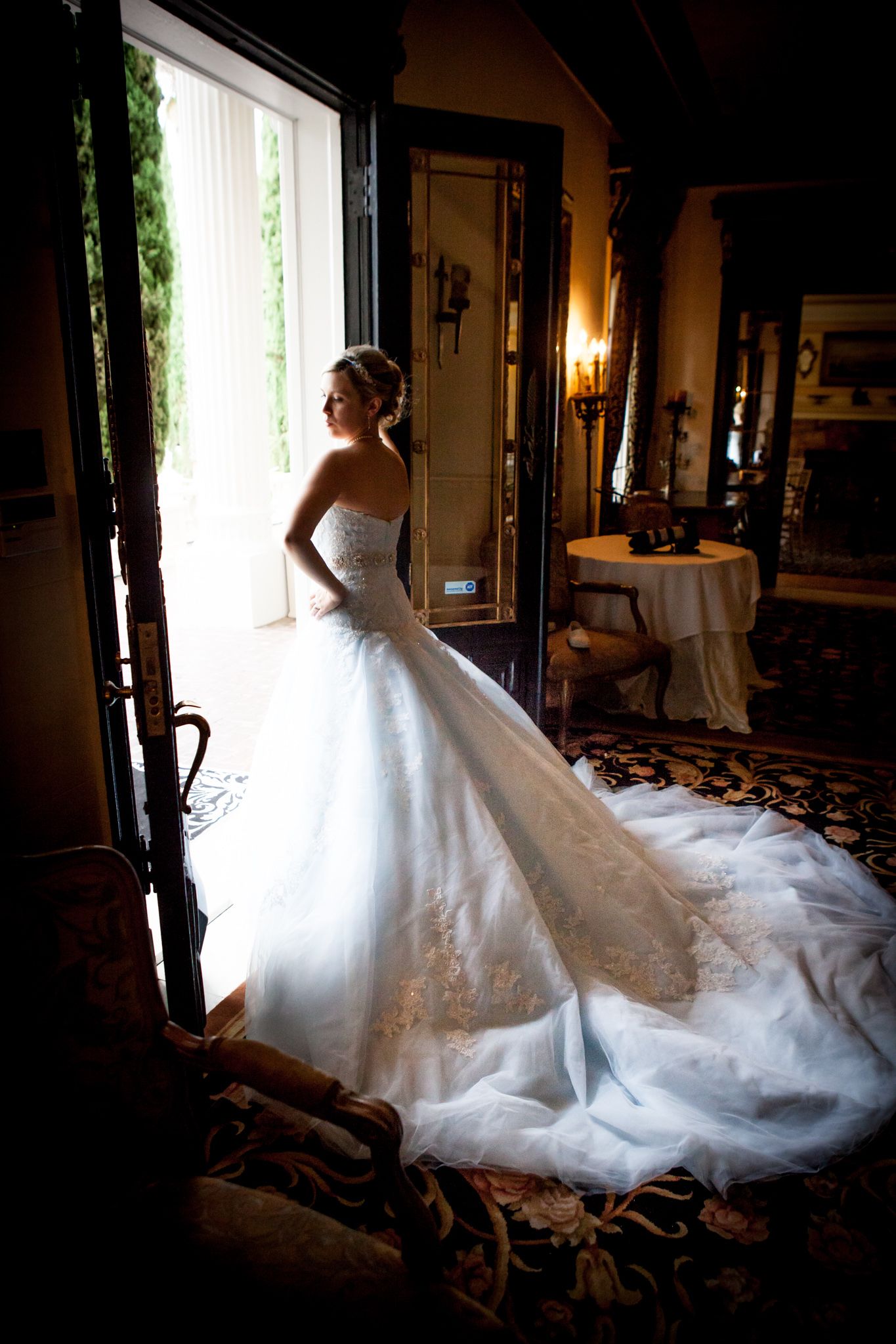 Silhouette of a wedding dress with dramatic train photographed in window light.