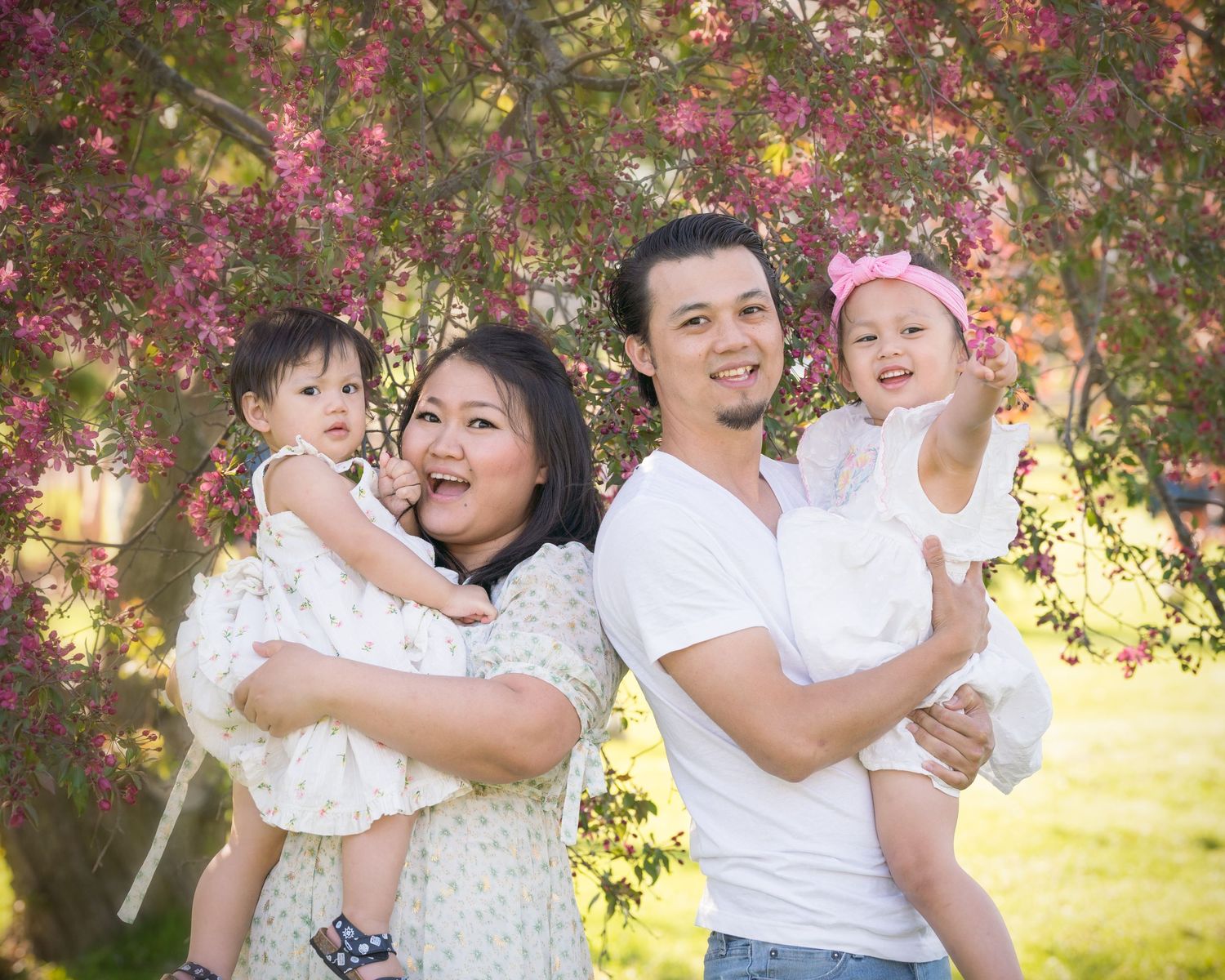 Family portrait under blooming cherry blossom trees in springtime.