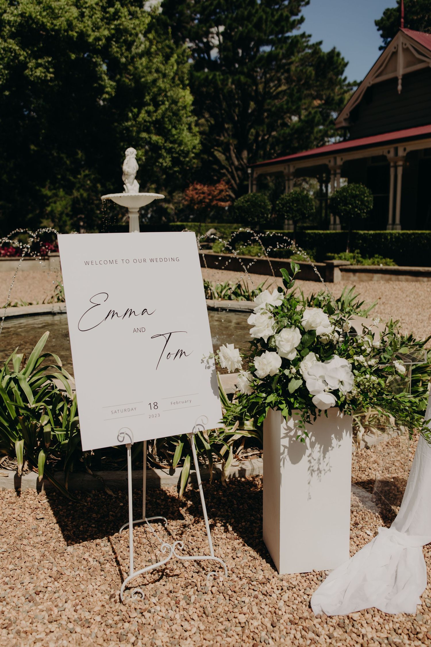 White floral wedding signage and decorations arranged along a gravel pathway.