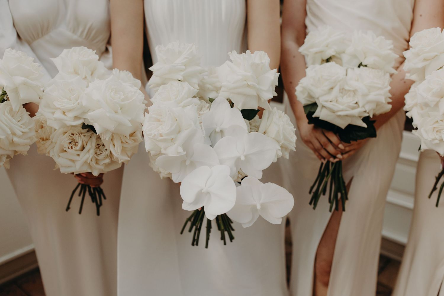 Close-up of white peony bouquets held by bridesmaids in matching dresses.