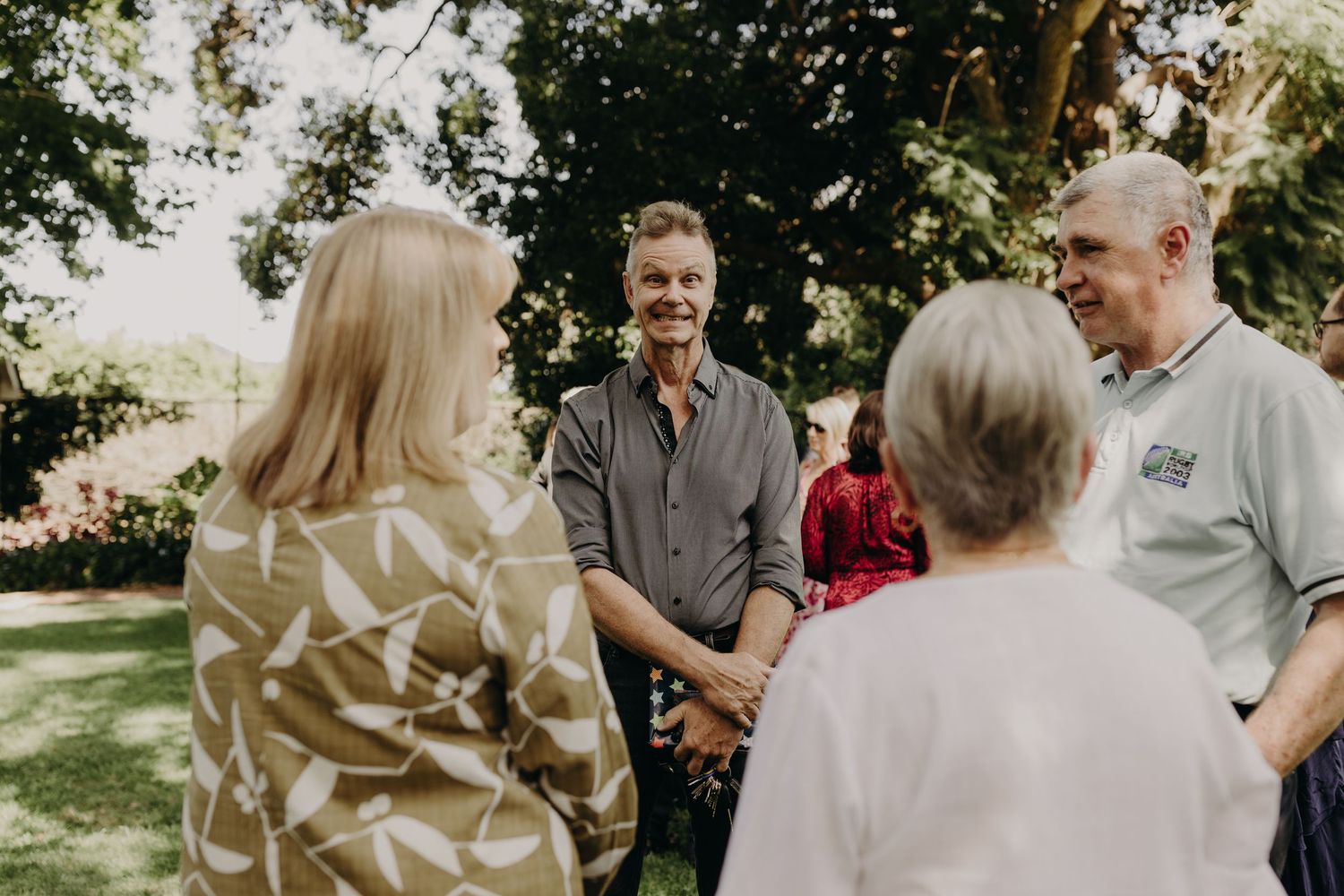 Wedding party shares joyful moments in a garden setting with natural lighting and greenery.