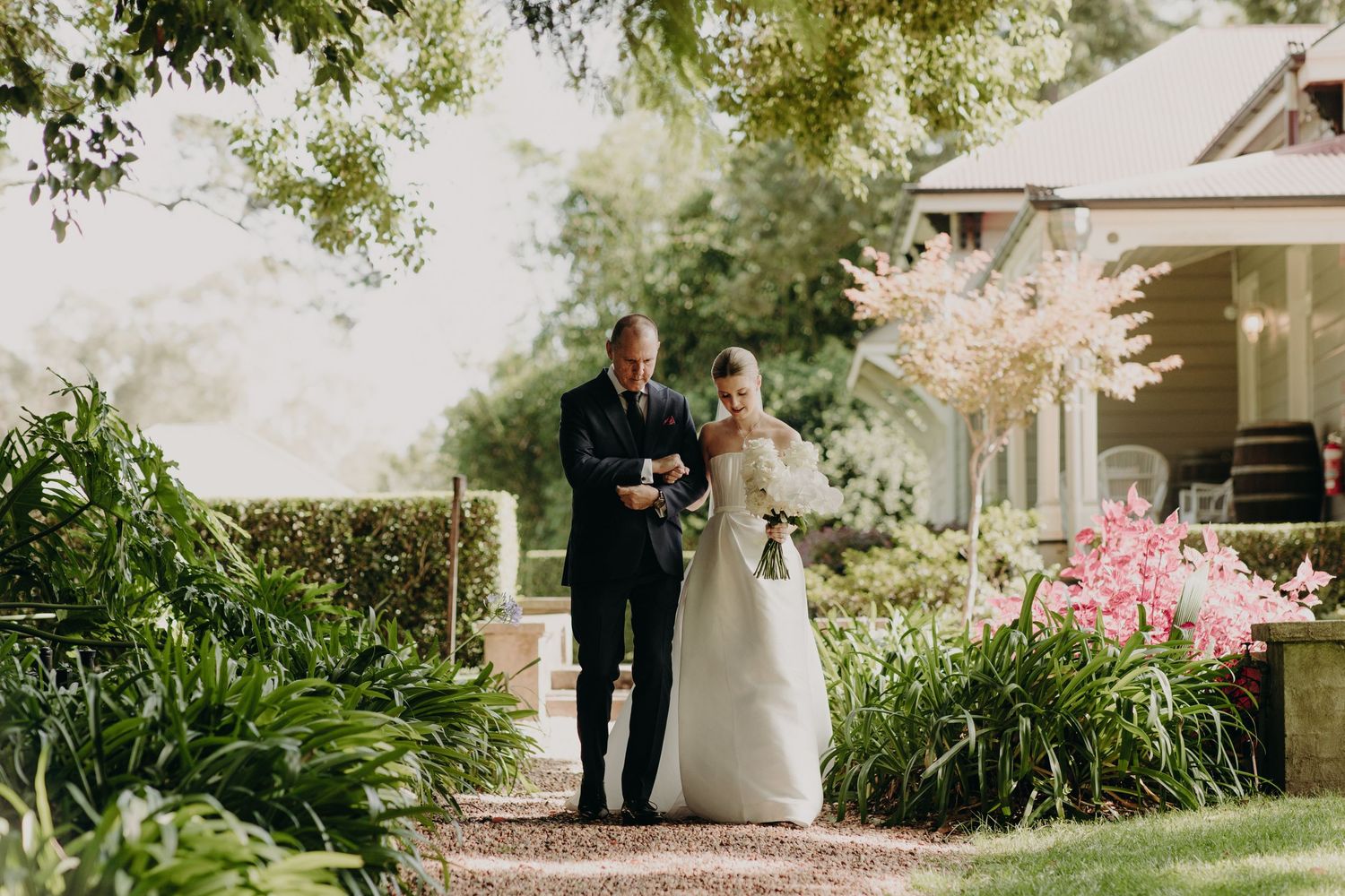 Elegant outdoor wedding ceremony setup with white chairs and floral arrangements.